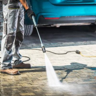 Cobble Driveway Pressure Washing by Caucasian Worker.