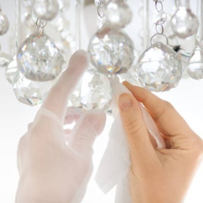 closeup of hands cleaning the chandelier with rag